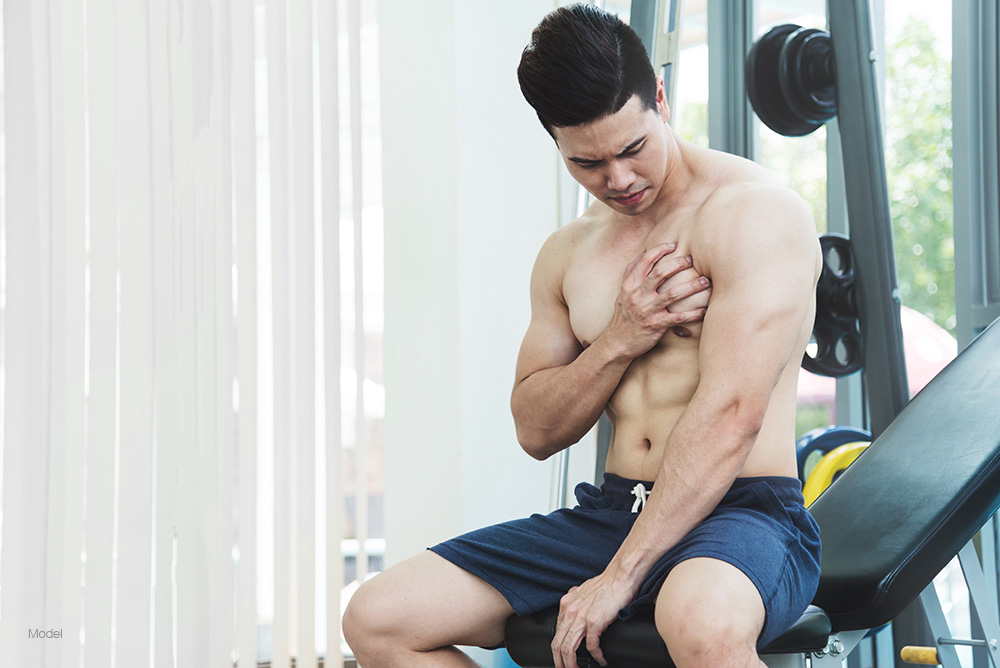 Fit shirtless man sitting at a workout bench
