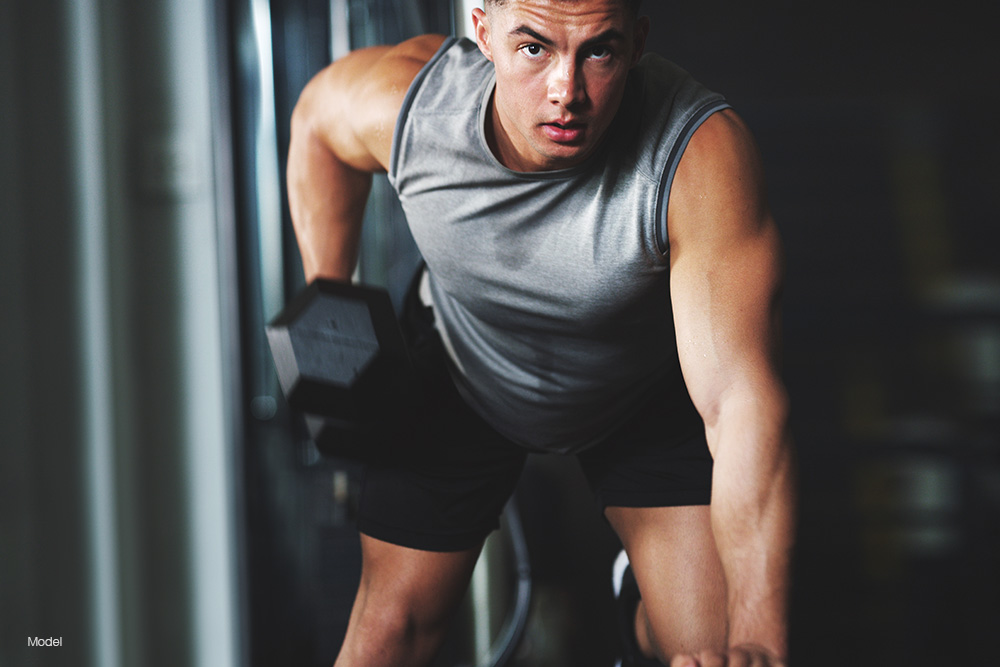 A fit man in a gray sleeveless shirt working out
